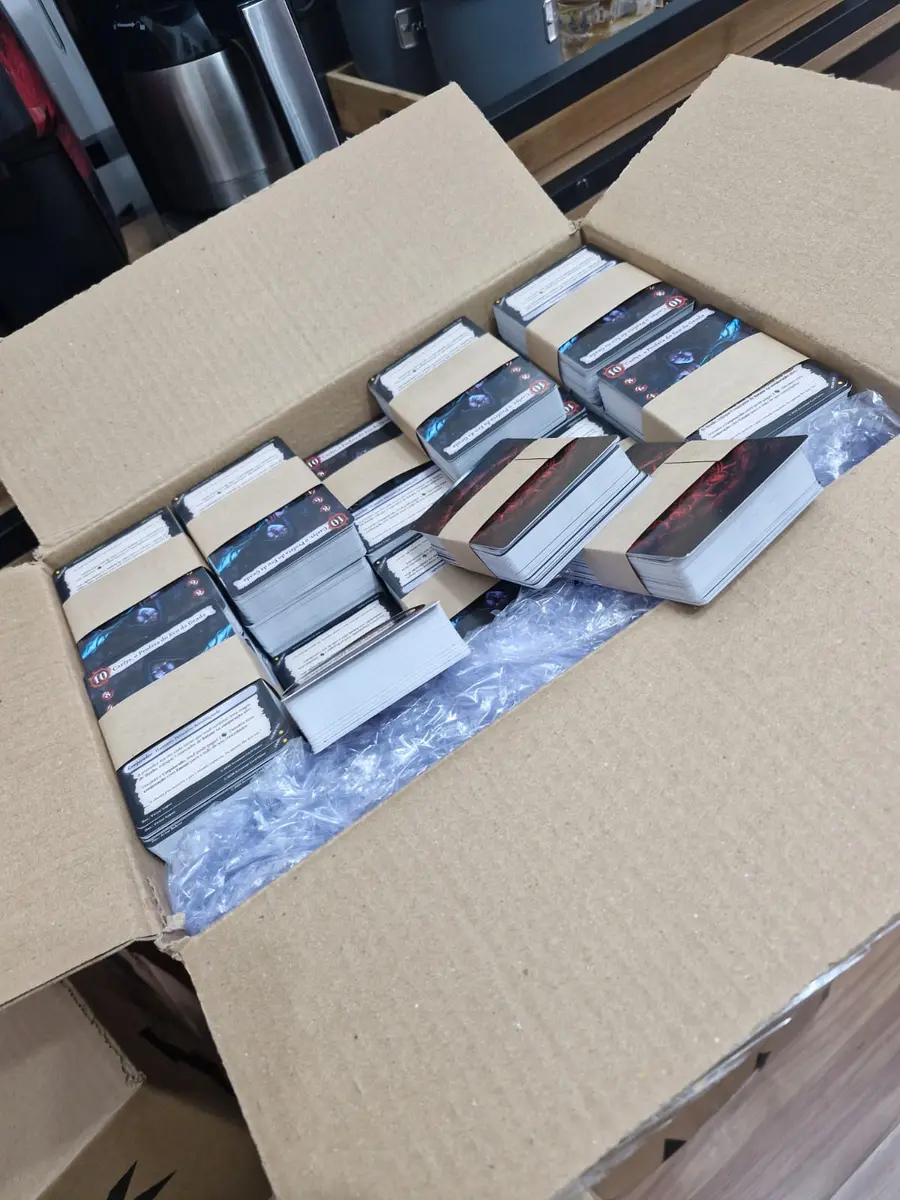 Caixa cheia de pilhas de cartas do Arcanum, com blocos de verso azul e verso vermelho